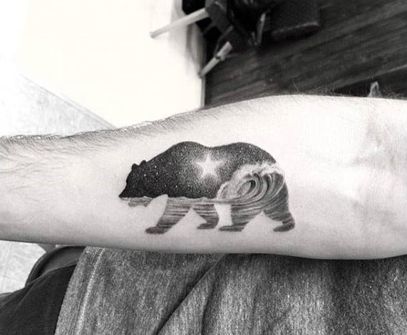 Black and grey tattoo of a bear silhouette filled with a starry night sky and crashing ocean wave, symbolizing strength and nature's duality.