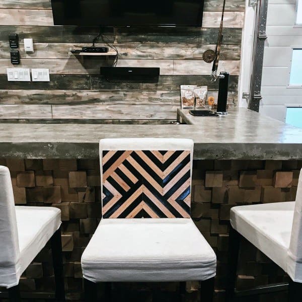 Modern garage bar with concrete countertop, geometric chair design, and reclaimed wood accents.