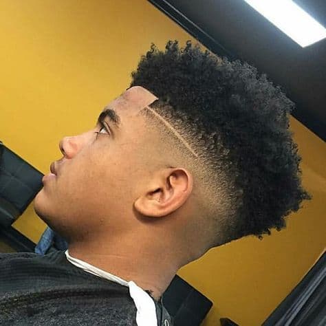 Mid length curly hair on top paired with mid-faded sides and back with a clean line slightly above the ear
