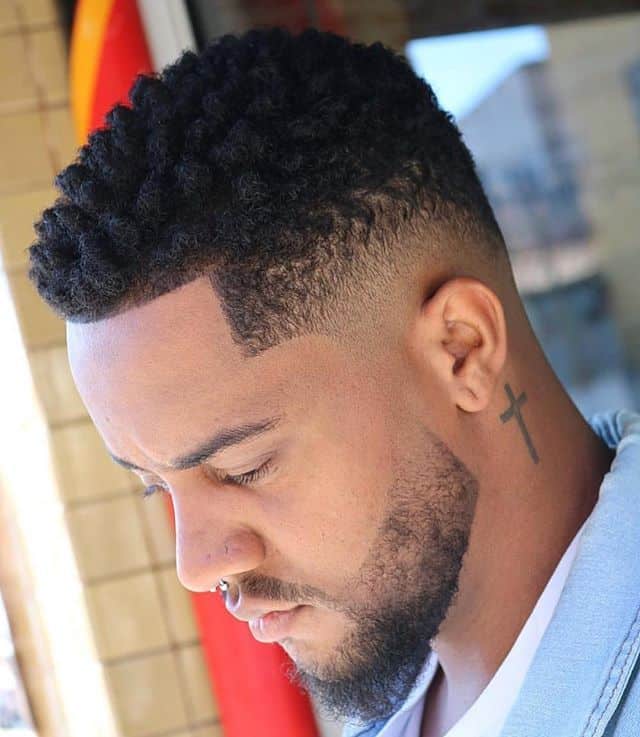 A black man wearing textured hair on top and medium faded sides paired with beard