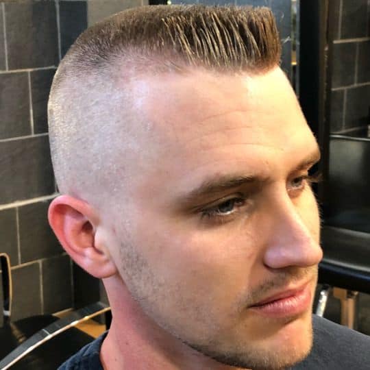 A medium fade cut featuring a hard part and short hair in front