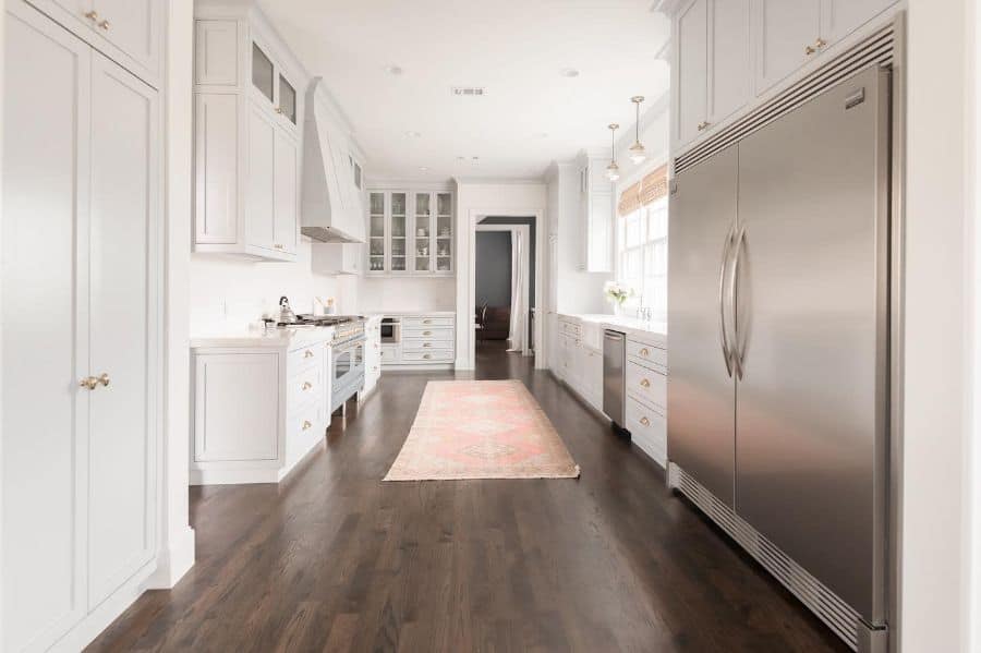 minimalist galley kitchen white cabinets gold accents hardwood floor 