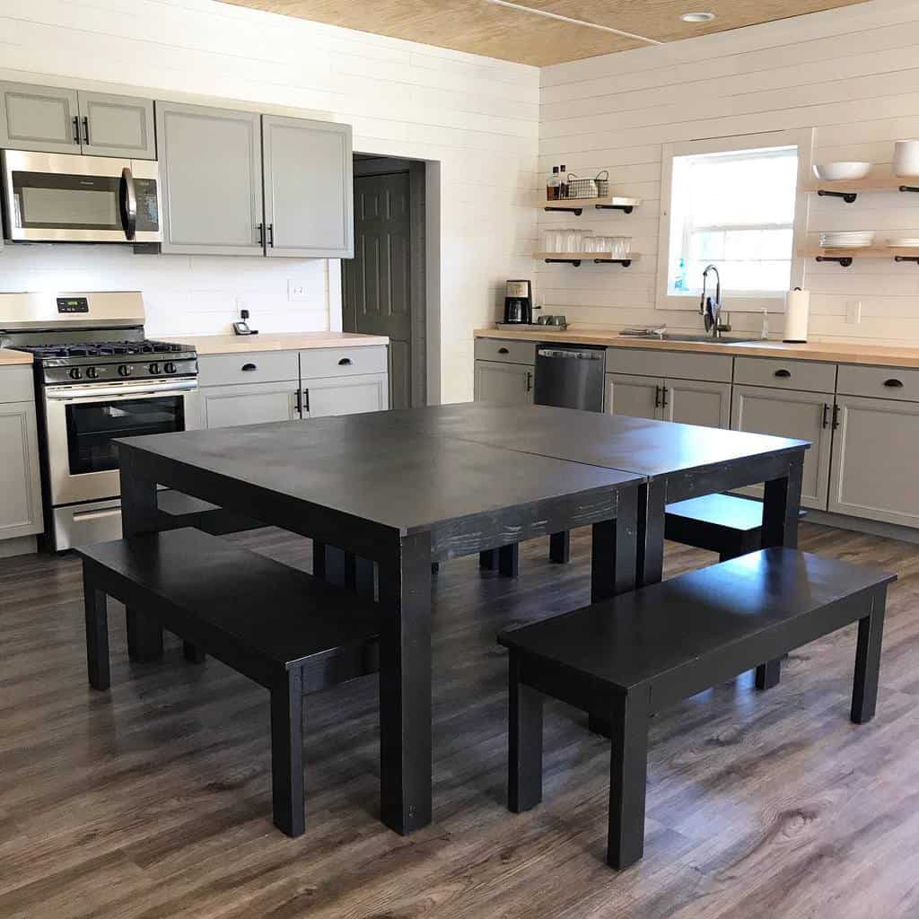 spacious modern farmhouse kitchen gray cabinets wood wall shelves black wood table and benches 