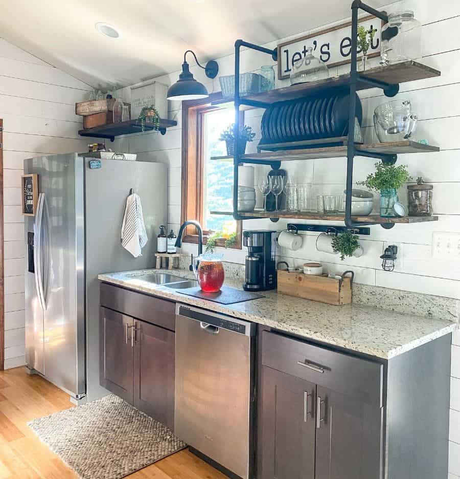 rustic farmhouse kitchen marble countertop silver appliances wood wall shelf with cutlery 