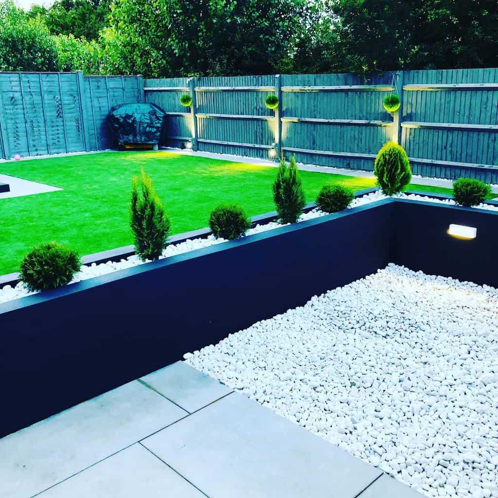 large modern garden lawn area wood fence black retaining wall 