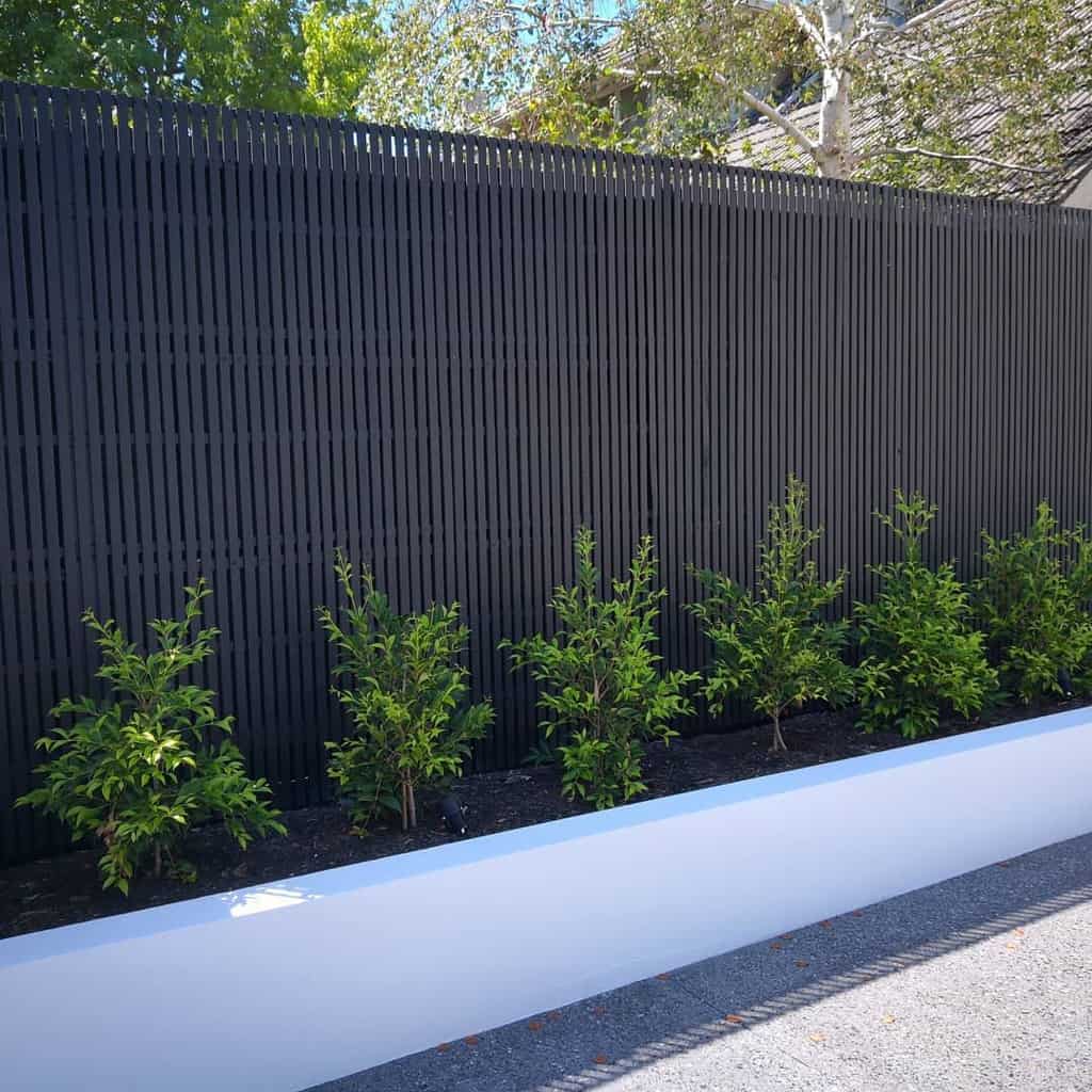 modern garden metal wall white retaining wall green shrubs 