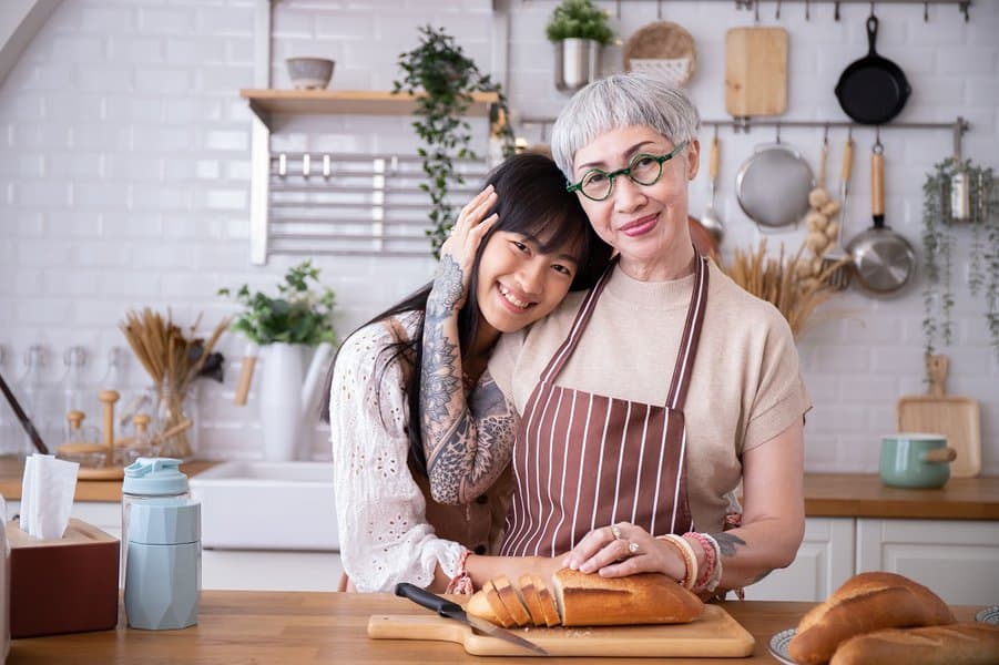 mother and daughter with tattoos hugging each other in the kitchen