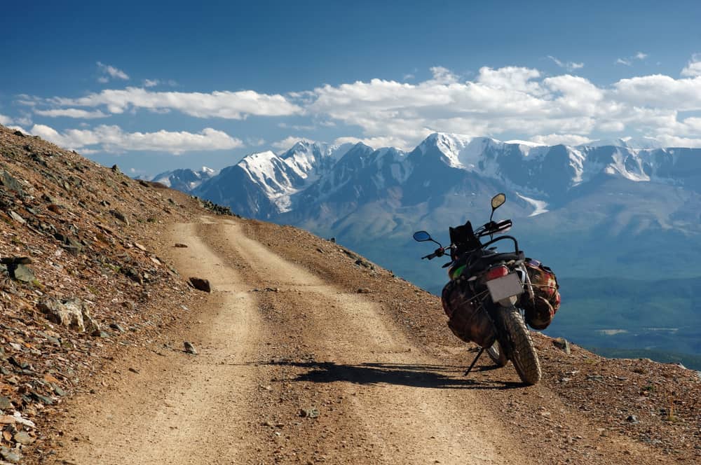 motorcycle enduro traveler standing alone on yellow stone extreme road