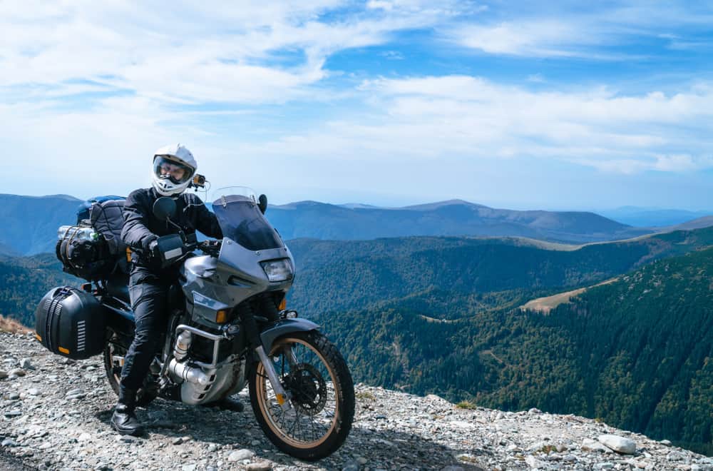 motorcyclist man with adventure motorbike on top of the mountain