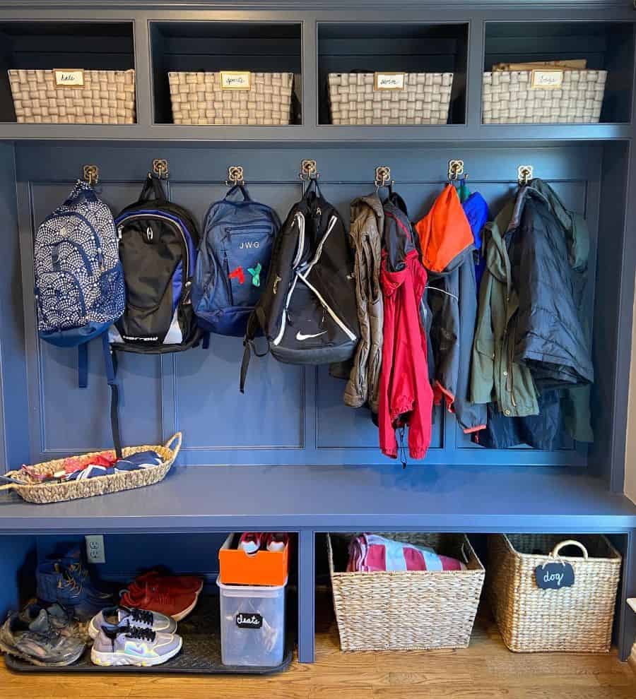 blue wood mudroom with bench seating weaved basket storage and coat hooks