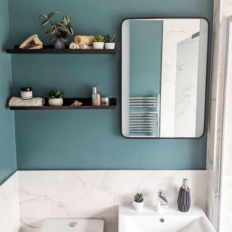 green wall bathroom with wall shelves and mirror 