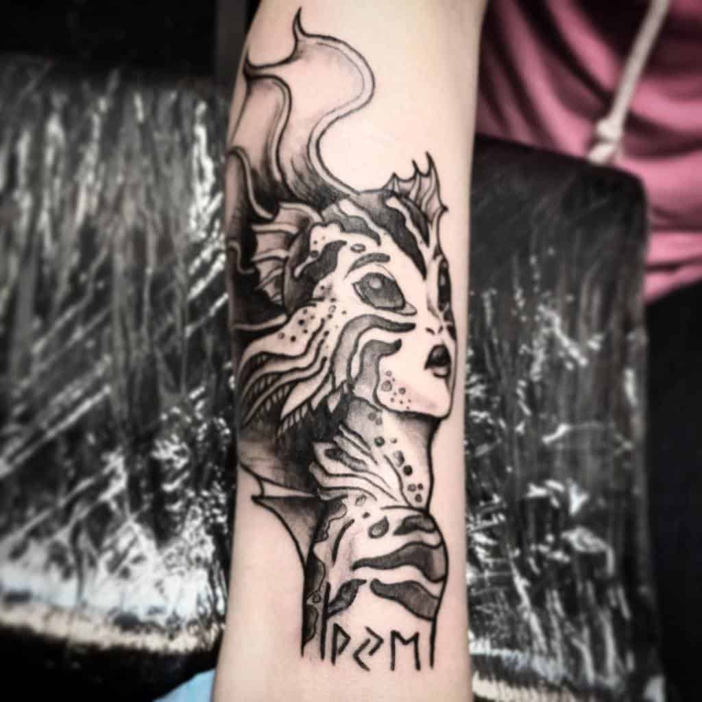 Unique forearm tattoo of a mystical siren with aquatic features, intricate fins, and bold black shading