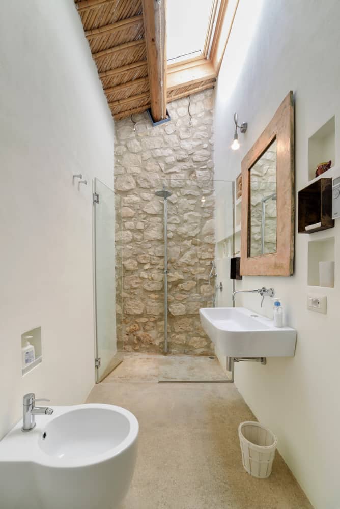 narrow bathroom with stone stone and skylight 