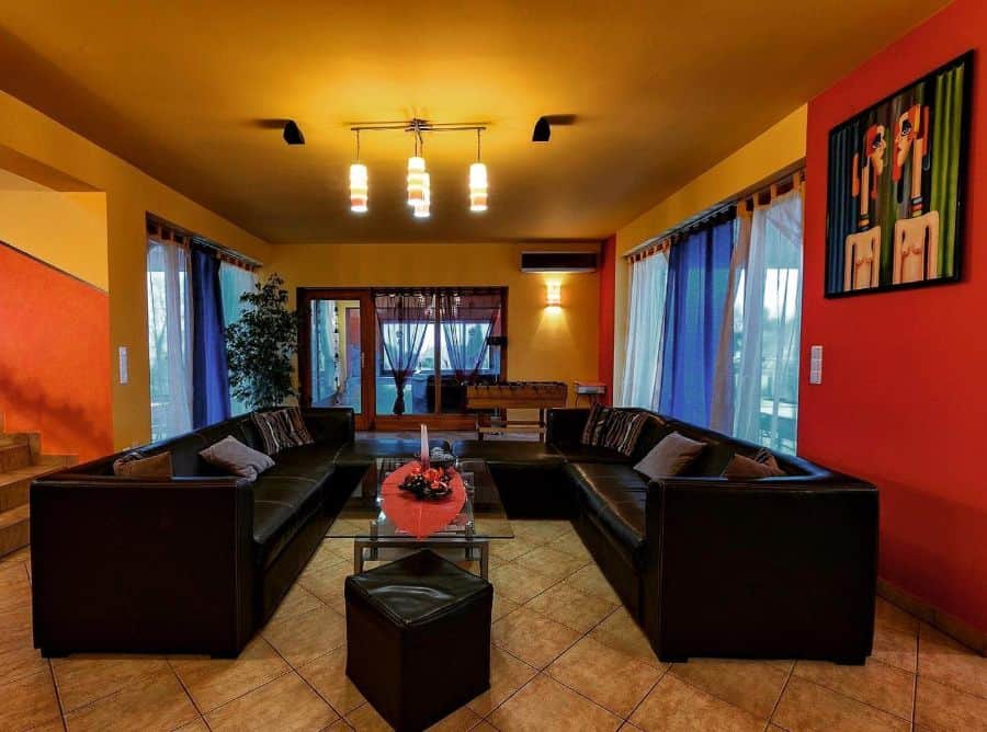 narrow long living room with red accent wall and black sofa