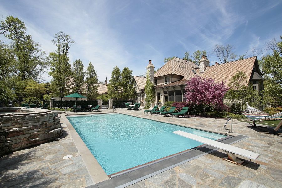 luxury home with stone paver pool patio with diving board