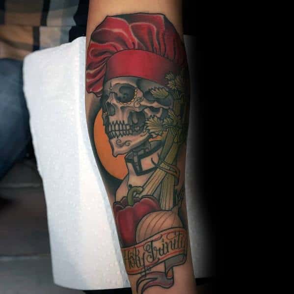 Detailed tattoo featuring a skull wearing a chef's hat, surrounded by onions, herbs, and a banner, blending realism with bold colors and shading.