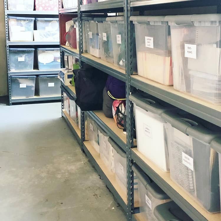 Organized basement shelves with labeled transparent bins for storage and various household items.