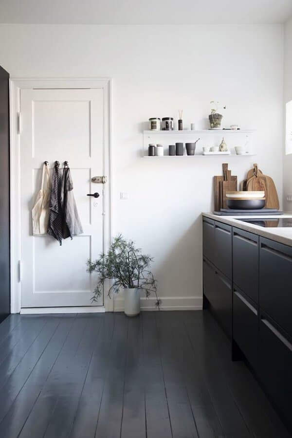 Kitchen with charcoal painted floor, white walls, black cabinets, and simple open shelving.