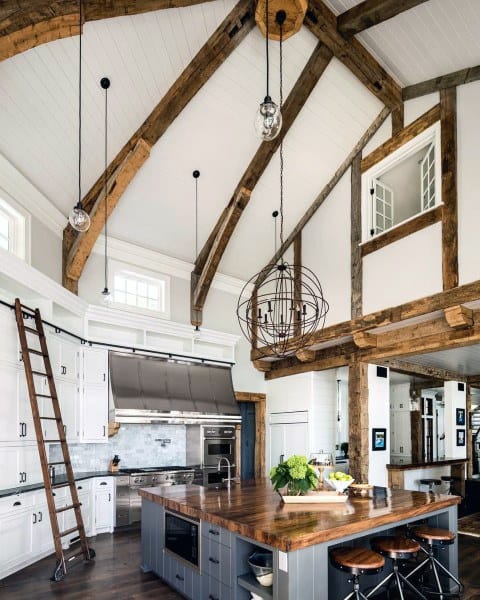 high ceiling kitchen with white cabinets gray island and decorative ladder 