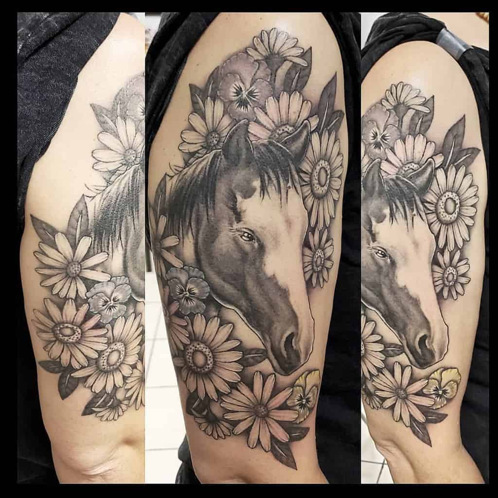Shoulder tattoo large realistic black and grey horse head framed by pansies and daisies