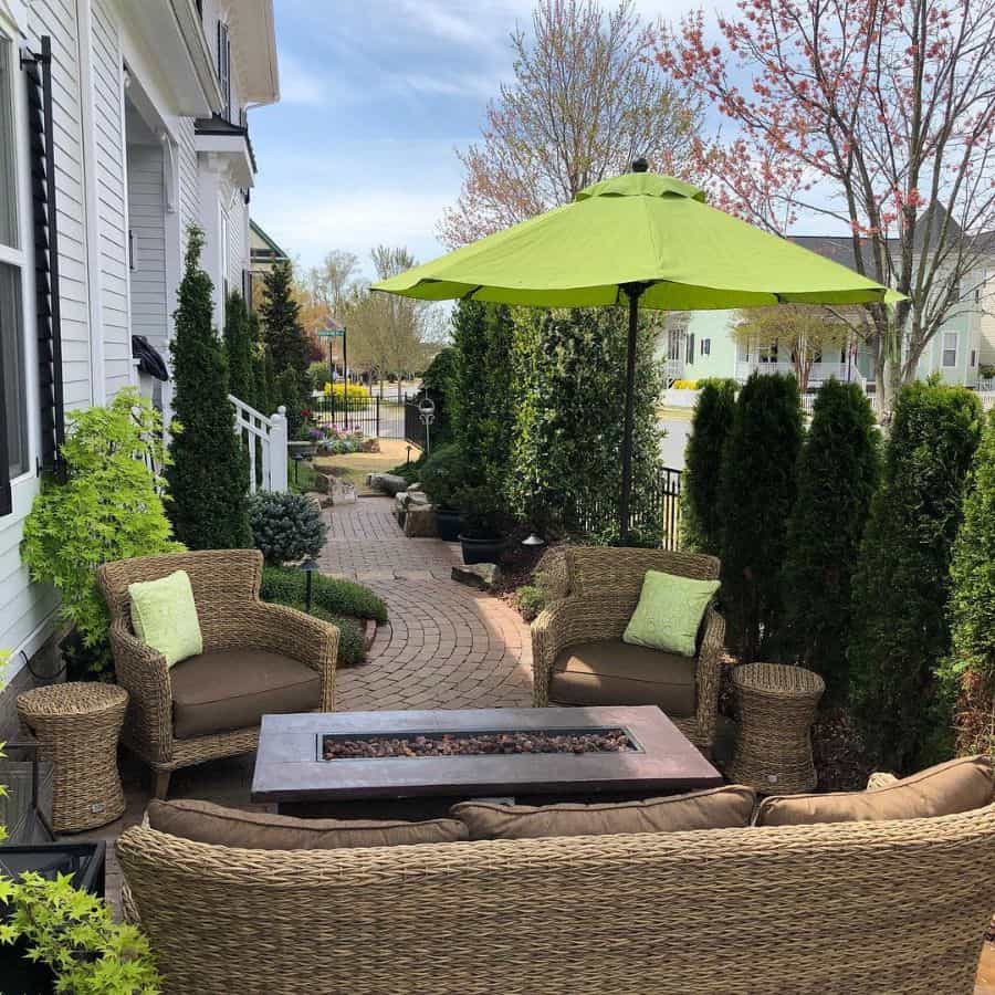 wicker furniture on brick patio with fire pit and green umbrella