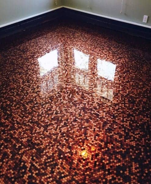 Room with glossy epoxy penny tile flooring reflecting natural light from large windows.