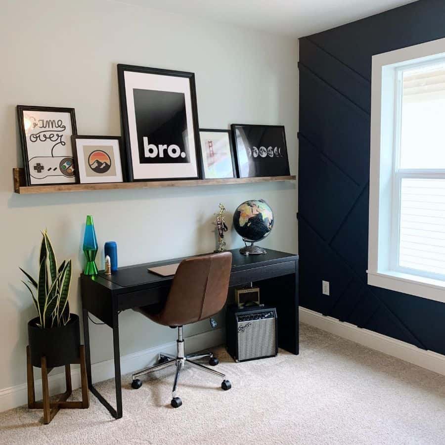 small home office with wood wall shelf holding framed drawings 