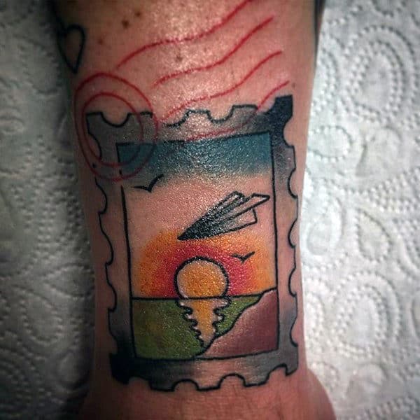 Postage Stamp With Sunset And Paper Airplane Mens Wrist Tattoos