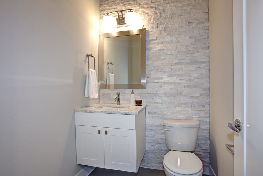 modern half bathroom with stone accent wall