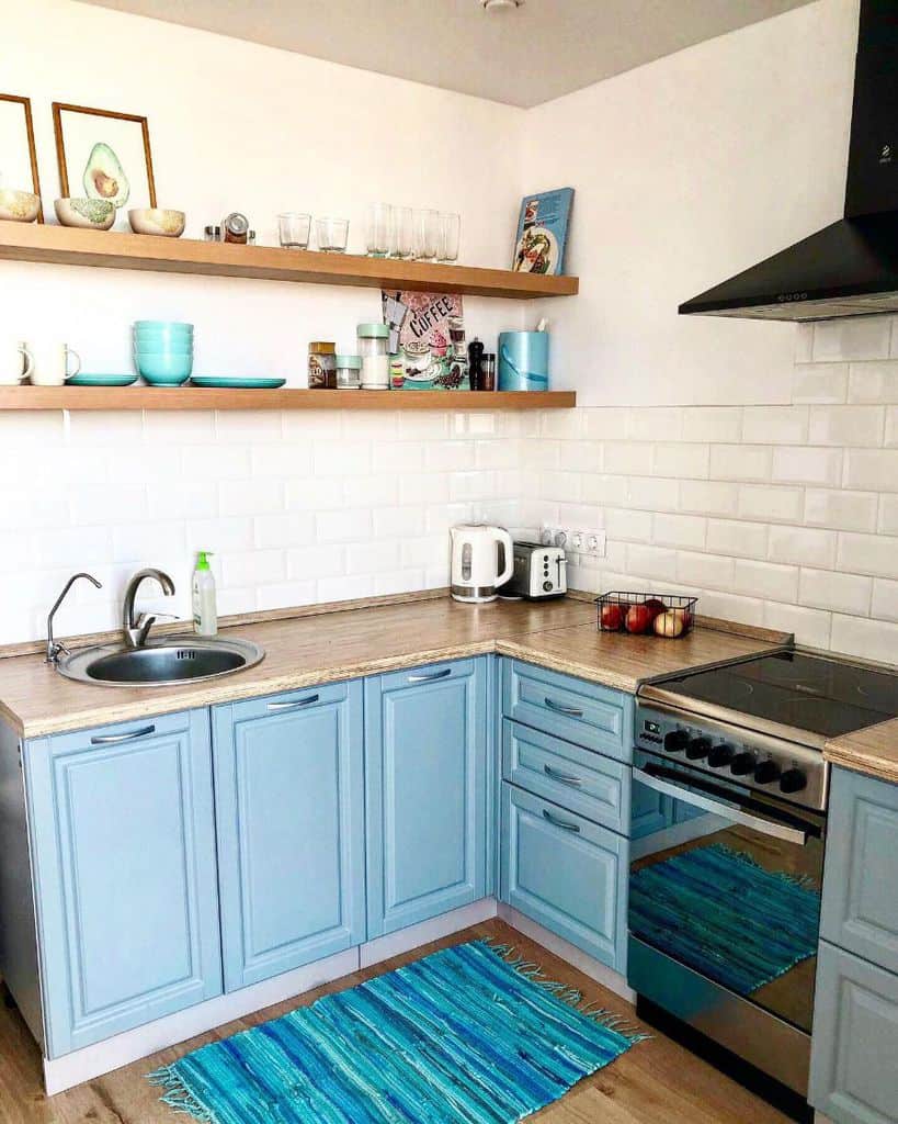 blue cabinet kitchen white tile backsplash wood floating wall shelves 