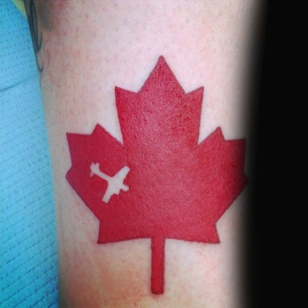 Red Ink Canadian Maple Leaf With Negative Space Airplane Tattoo On Man