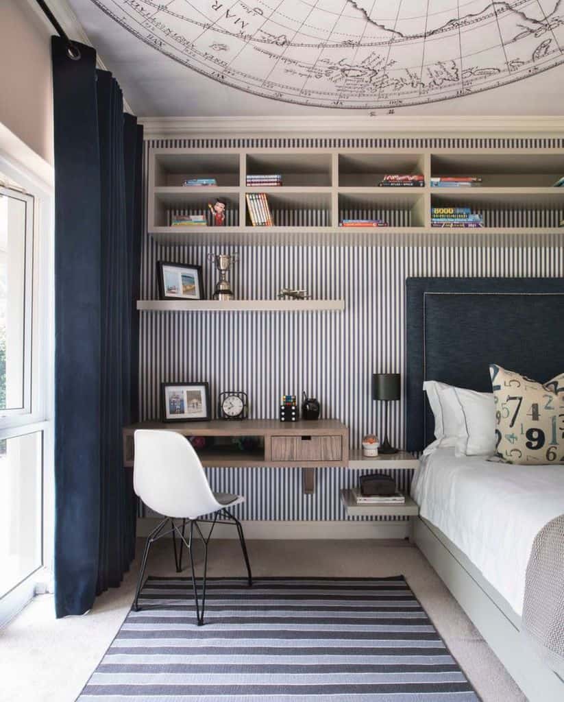 Boys' bedroom with world map ceiling, wall shelves, brown desk, and striped rug.