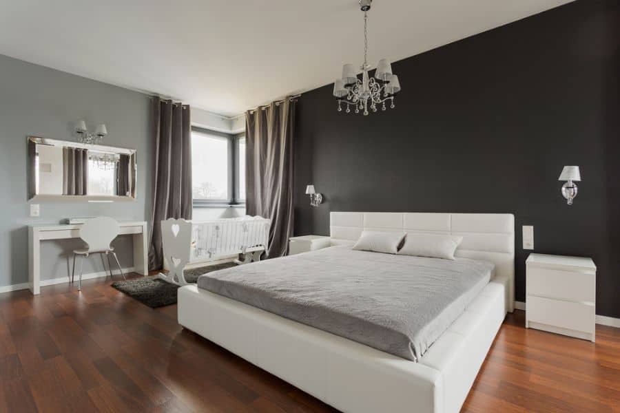 large simple bedroom white bed and crib black feature wall floorboards