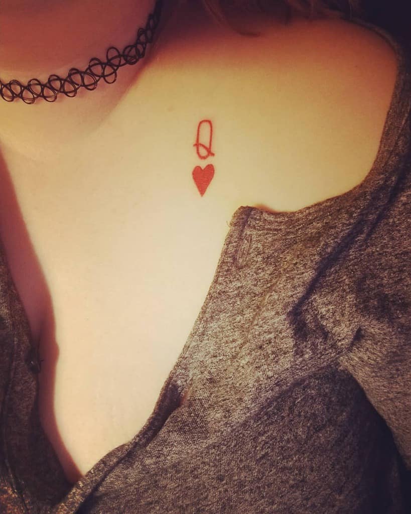 Tattoo of a red queen of hearts symbol on a shoulder