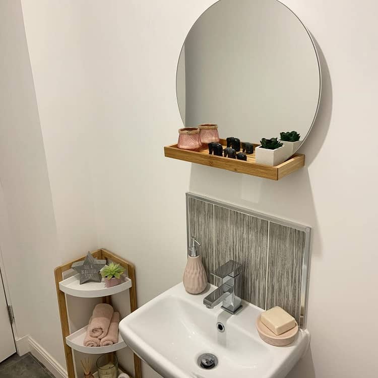 small bathroom with corner towel storage shelf