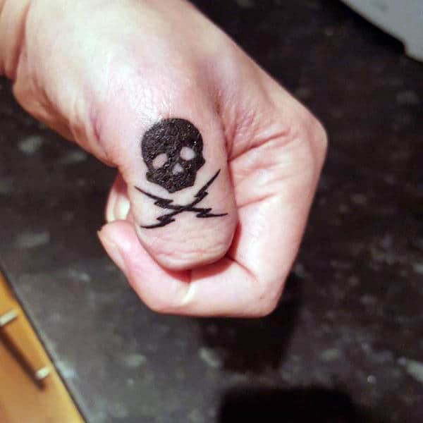 Skull With Crossed Lighting Bolts Thumb Tattoo On Man