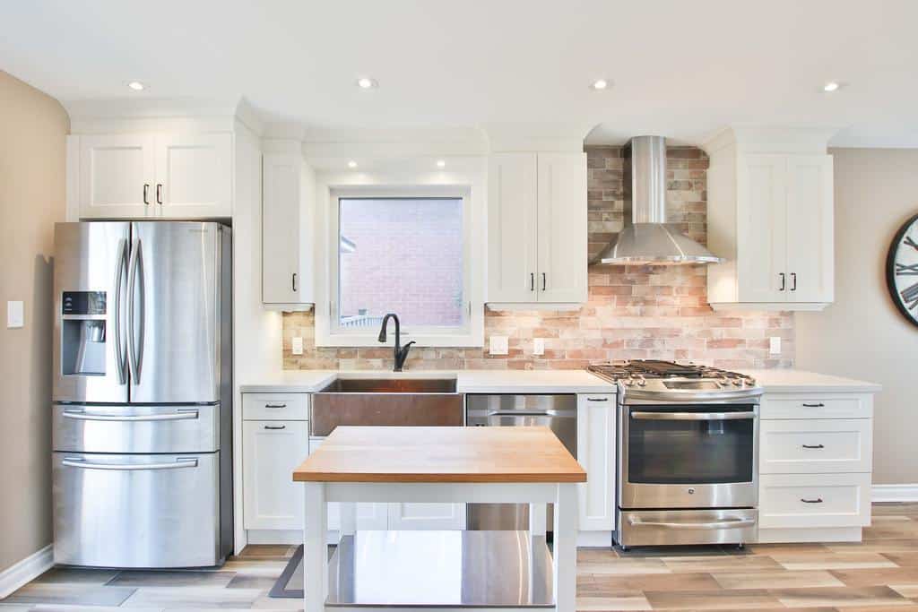 brick wall splashback white cabinets silver appliances 