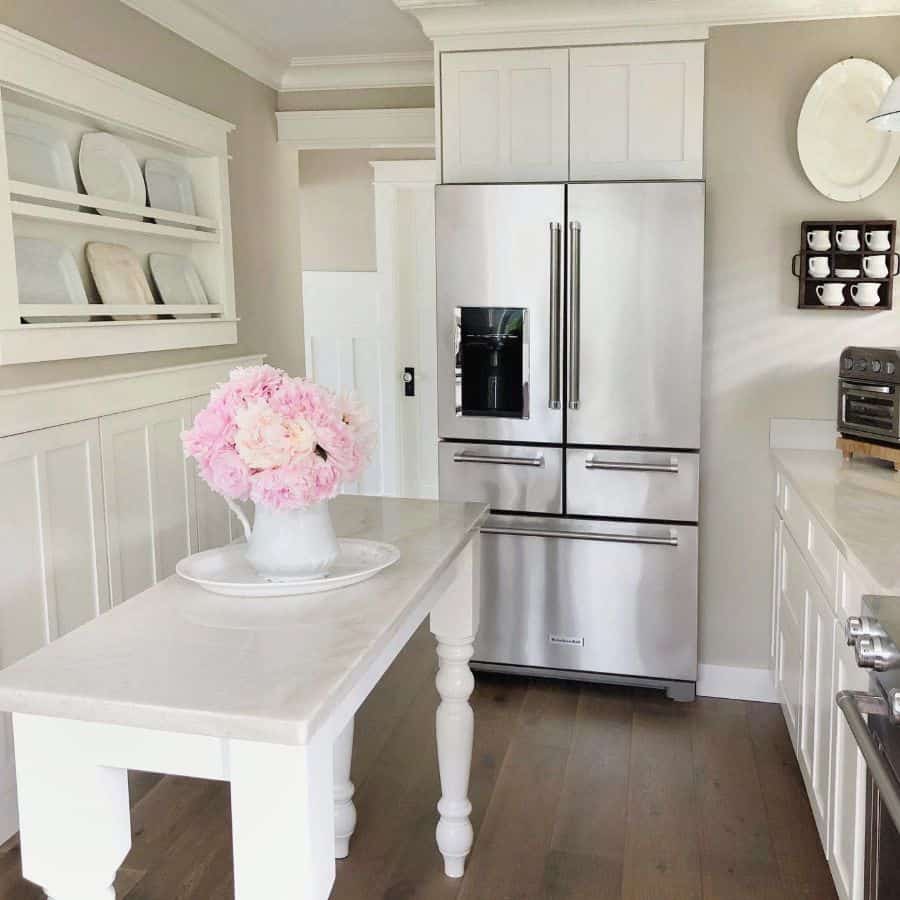 small white farmhouse kitchen vase of pink flowers silver fridge 