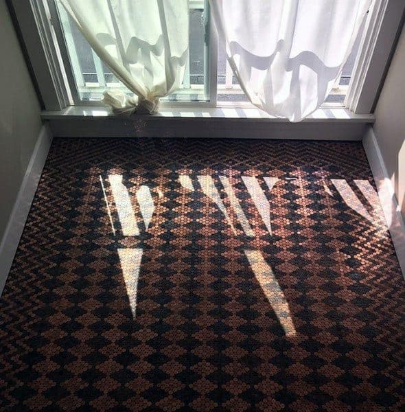 Room with patterned penny tile flooring and sheer curtains framing natural light from windows.