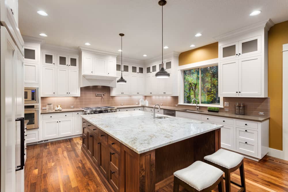 large farmhouse kitchen white cabinets wood island with marble countertop pendant lighting 