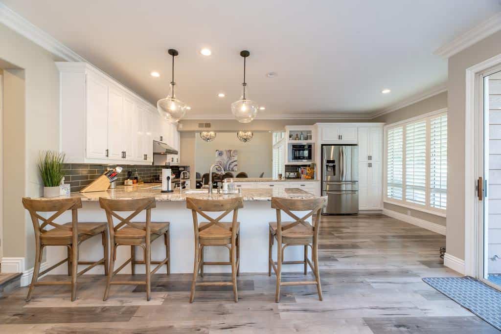 huge farmhouse kitchen white cabinets gray tile splashback wood chairs 