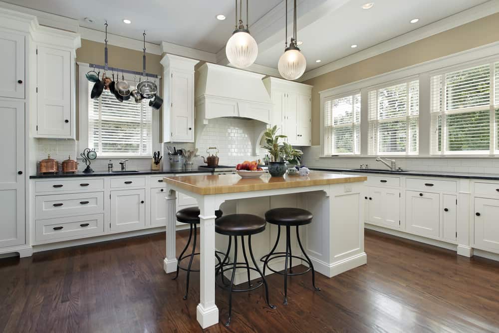 spacious farmhouse kitchen white cabinets white island with wood countertop black stools 