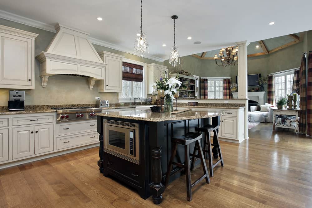 spacious luxury open plan farmhouse kitchen black island white cabinets chandelier