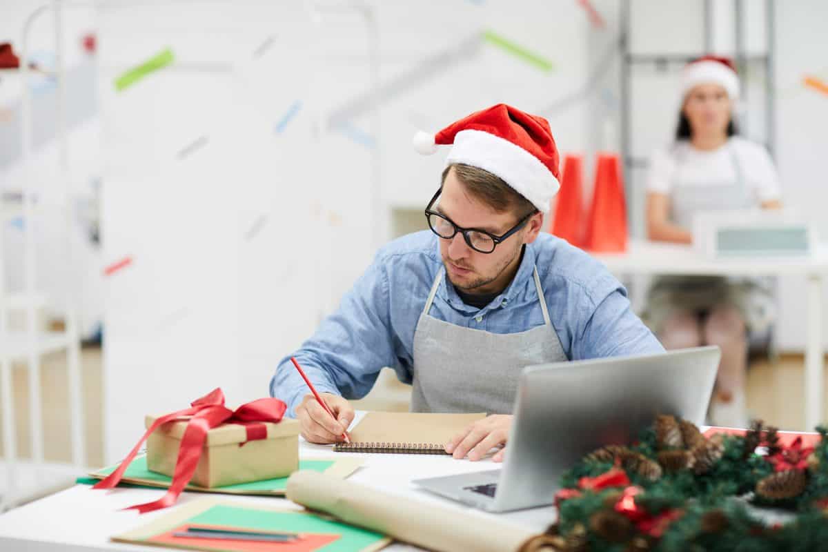 Serious,Concentrated,Young,Male,Designer,In,Santa,Hat,Sitting,At
