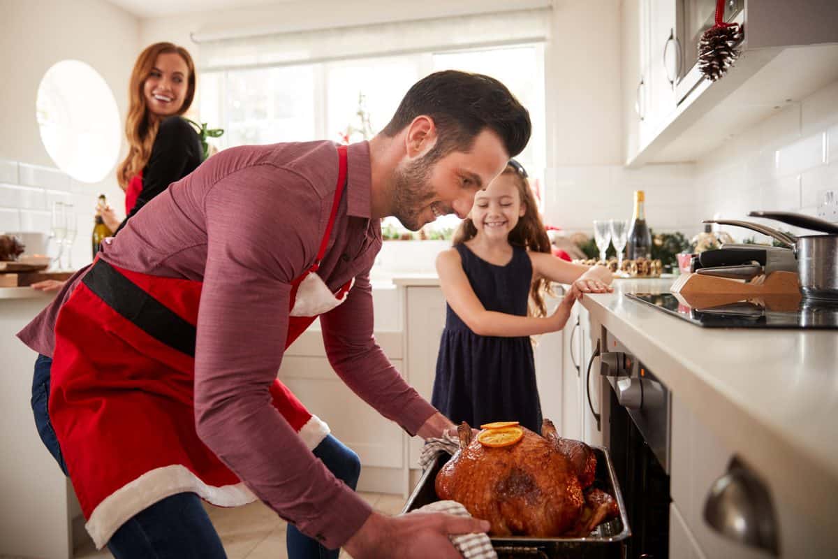 Father,Getting,Turkey,Out,Of,Oven,As,Family,Celebrate,Christmas