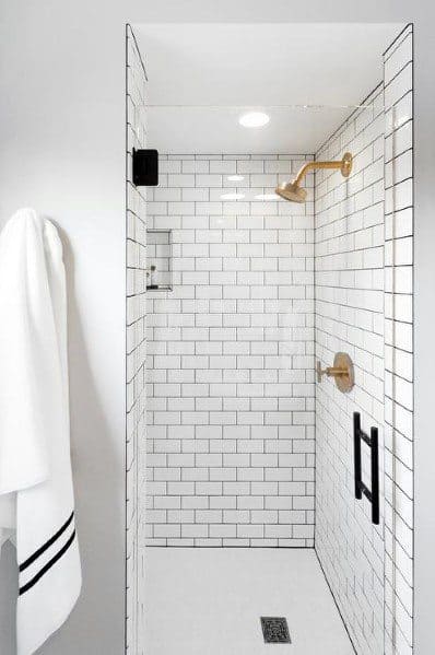 white tile shower with gold faucet 