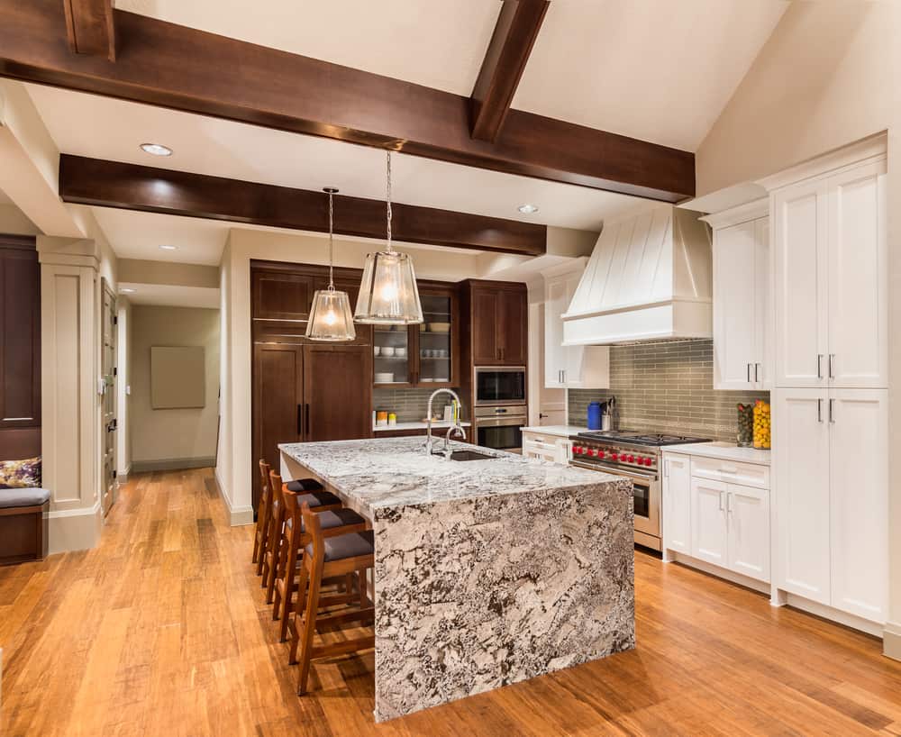 traditional farmhouse kitchen marble island wood chairs white and brown cabinets gray tile splashback 