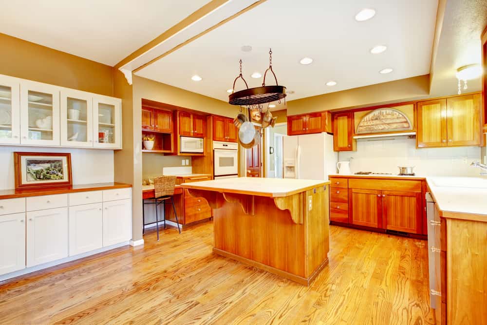 large traditional farmhouse kitchen wood cabinets and island hanging pots and pans