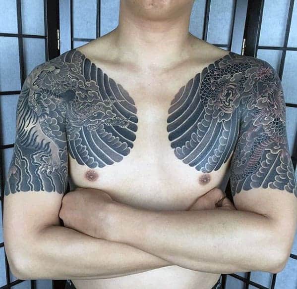 Traditional Japanese dragon tattoo spanning the chest and half sleeves, showcasing detailed scales and flowing clouds in black and gray