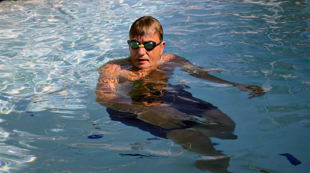 Man,Treading,Water,In,Swimming,Pool,Wearing,Goggles.